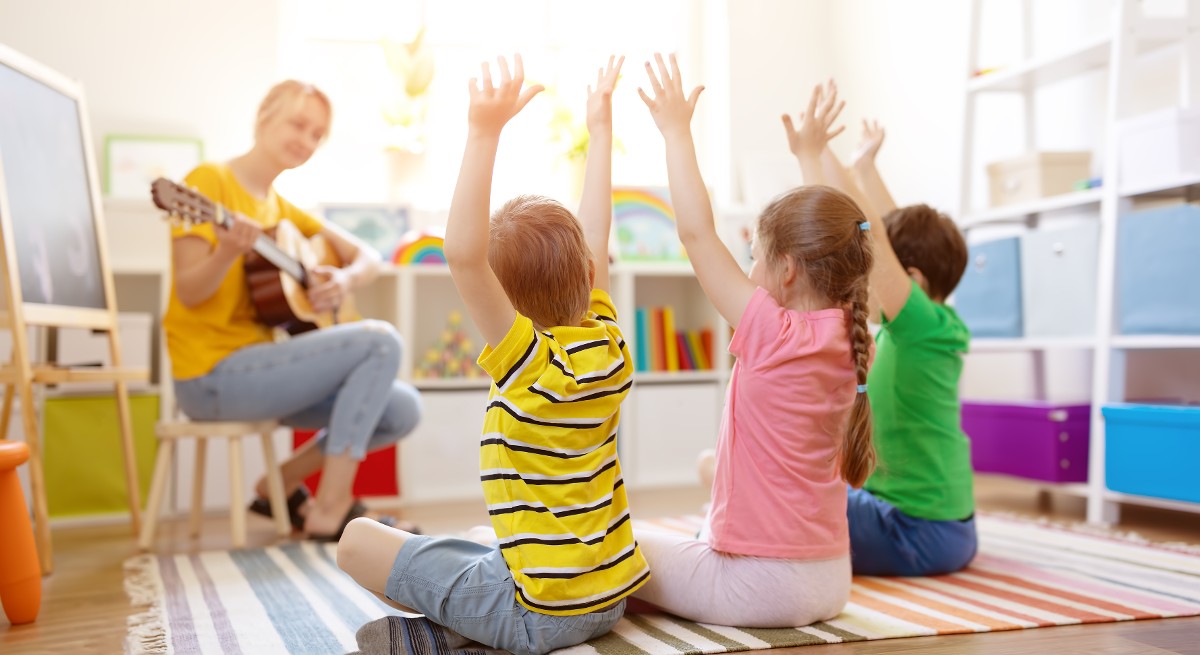 Kindergartenpädagogin spielt Gitarre und singt mit den Kinden